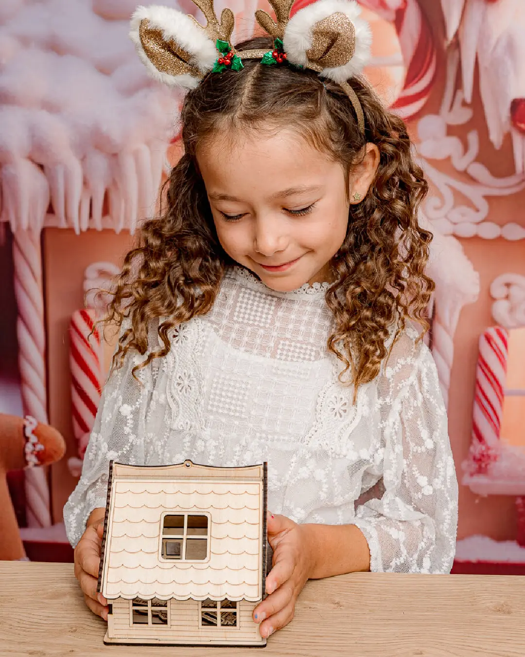 La petite fille regarde son chalet de montagne en bois avec fierté. Ateliers de création en bois pour les familles dans les stations de ski. Les enfants et les familles fabriquent un chalet en bois composée de 10 pièces en bois. Cette animation convient aux offices de tourisme est accessibles aux enfants dès 6 ans et leurs familles ! Cet événement est accessible avec et sans inscription aux enfants à partir de 6 ans et leurs familles. Ils décorent et assemblent leurs création. Ils repartent avec un chalet en bois gravés avec le nom de l'événement ou de la station de ski. Cette animation est à destination des stations de Savoie et offices de tourisme (Courchevel, Tignes, Val d'Isère, Sainte Foy, La Rosière, Les Arcs, Peisey-Vallandry, La Plagne, Val Thorens) et Haute Savoie (Megève, Combloux, Chamonix, Morzine les Gets, Annecy, Avoriaz, La Cluzaz...). Il le personnalise avec des mini-ski, des flocons, des étoiles, des sapins...